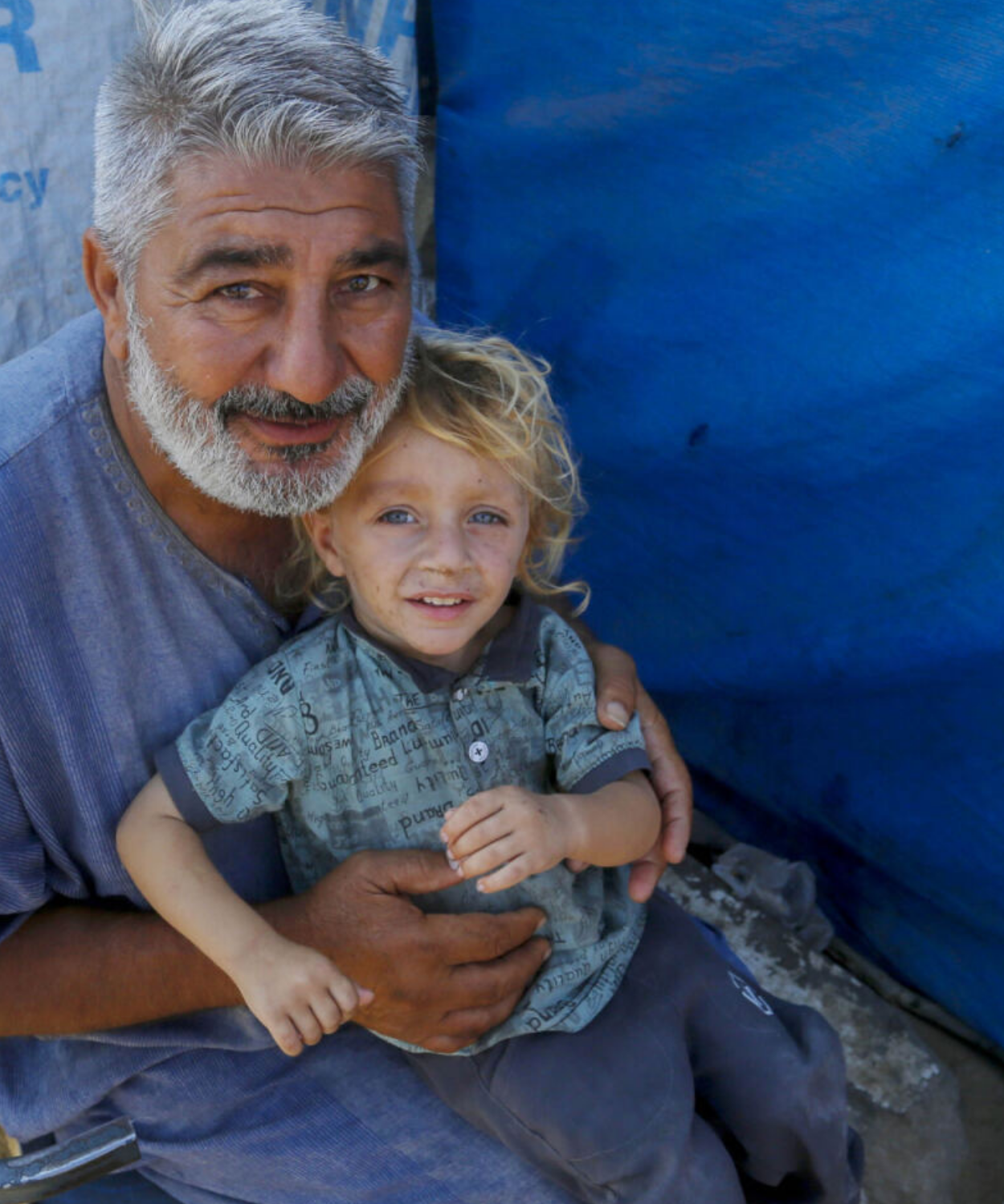 An old man that holds a small kid at one of UNRWA shelters
