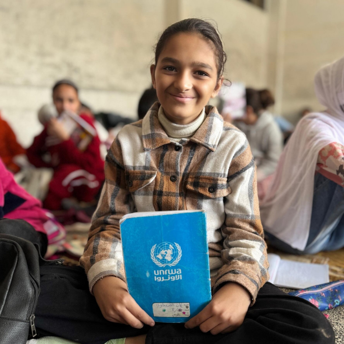 Young Palestine Refugee girl holding an unrwa notebook